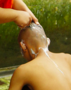 A young man having his head shaved.